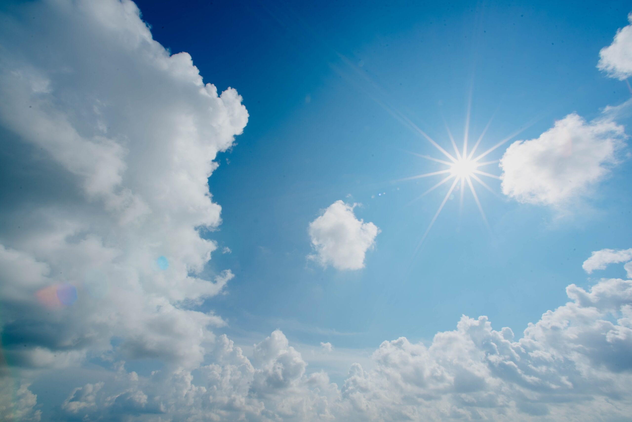 blue sky a border of clouds and the sun shining