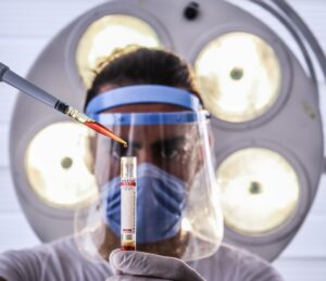 scientist with a clear face mask and a test tube in a lab