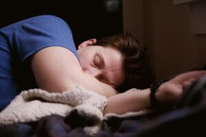a man sleeping on his side with a blanket bunched up in front of him