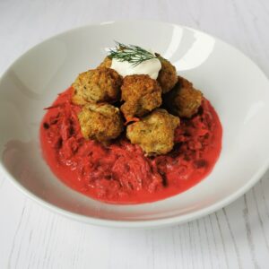 white bowl sitting on a white wood background with dill meatballs on top of fennel and beetroot