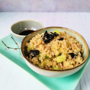 a bowl of quinoa sushi sitting on a green Japanese plate with accompanying tamari sauce.